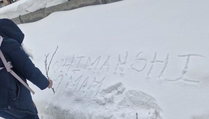 A student writes her name in the snow abroad